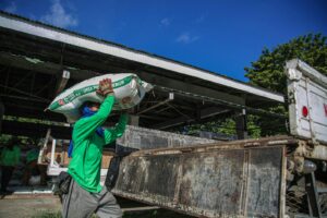 Man in Green Jumper Carrying White Bag on Head